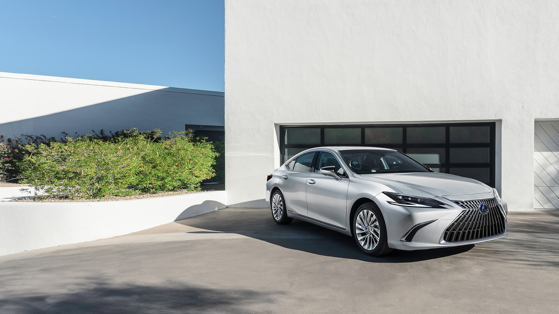Silver Lexus ES is parked next to a white house.